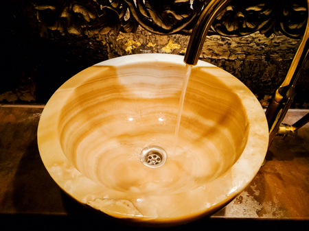 Vintage Beautiful faucet and golden mixer on a marble sink in a bathroom. Interior of expensive toilet with marble washbasin. retro tap and Closeup shotの写真素材