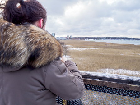 Young  tourist girl take Pictures by smartphone overlooking Baltic sea, Back view. vacation concept....