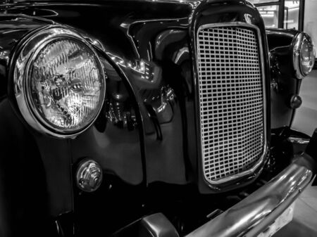 TALLINN, ESTONIA- SEPTEMBER 19, 2019: Front view of a black retro car. Black old car with headlamp and chrome radiator grill. Photo of a headlight of a Classic vintage retro automobile. Filtered imageのeditorial素材