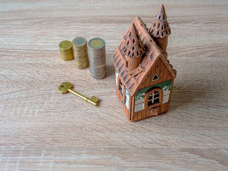 Model of a house, Stack of European Euro coins and golden key On Wooden Table. Real estate agency, mortgage loan, lottery, buying property.Home loan and investment concept. Copy spaceの写真素材