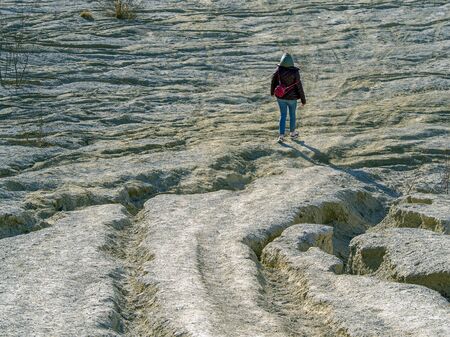 young woman with red jacket and abndoned Quarry Of Rummu, Estonia on the background. Scenic View Of Land Against Clear Blue Sky. Panoramic View. の写真素材