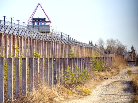Old observation tower in abandoned Soviet Russian prison complex. Prison guarding tower, fence with barbed wire. Copy spaceの写真素材
