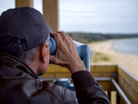 man looking through tourist binoculars. Hands on the telescope. ocean on the background. vacation conceptの写真素材