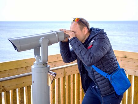man looking through tourist binoculars. Hands on the telescope. ocean on the background. vacation conceptの写真素材