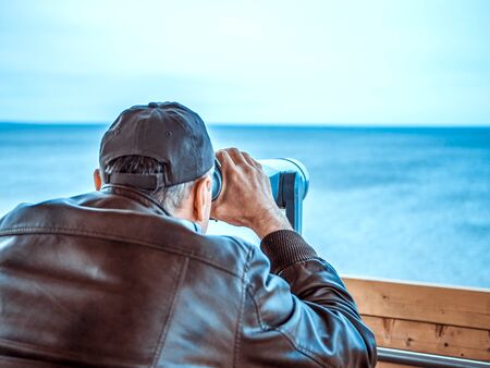 man looking through tourist binoculars. Hands on the telescope. ocean on the background. vacation conceptの写真素材