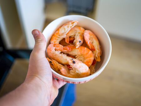 Bowl filled with fresh shrimps in man hands. Food for diet - Grilled shrimps with mango salad. Home cook in Asian kitchen.の写真素材
