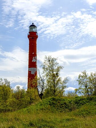 Bright day landscape. Red lighthouse against the cloudy sky. lighthouse on the rocky seashore in Estonia, Paldiski. copy space. hope conceptの写真素材