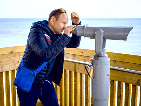 man looking through tourist binoculars. Hands on the telescope. ocean on the background. vacation conceptの写真素材