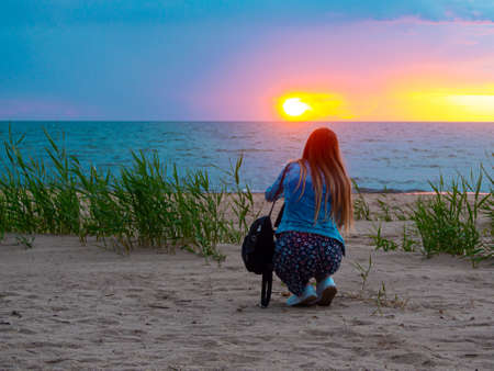 beautiful alone girl on the beach. Girl looking at stormy sea amd taking a picture with smarphone....