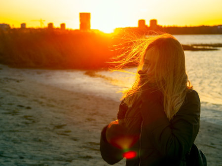 Silhouette of a lonely woman watching sunset in autumn. downtown buildings silhouettes. Nature Orange sea sunset in the city landscape beautiful landscape of Tallinn skyline Panoramic view on beachの写真素材