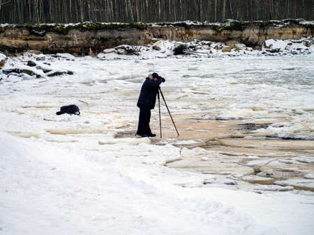 the photographer takes photos of sea, winter time. cliff on the coast of the Baltic sea. Suurupi in Estonia. Rocky Coasline. vacation and freedom concept. The view of big icicles and frozen waterの写真素材