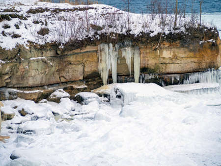 Trees a mountain pick, winter time. cliff on the coast of the Baltic sea. Suurupi in Estonia. Rocky Coasline. copy space. vacation and freedom concept. The view of big icicles and frozen waterの写真素材