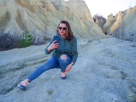 Hiker on mountain top with smartphone. Woman is standing and taking a picture on smartphone. Abandoned Quarry Of Rummu, Estonia. Scenic View Of Land Against Clear Blue Sky. Panoramic View.の写真素材
