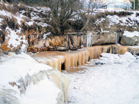 Trees a mountain pick, winter time. cliff on the coast of the Baltic sea. Suurupi in Estonia. Rocky Coasline. copy space. vacation and freedom concept. The view of big icicles and frozen waterの写真素材