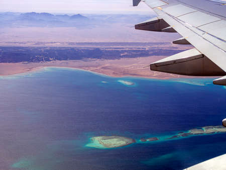Aerial view above the clouds and sky, Inspiration concept. Travel freedom by air. Flight, view from the airplane to tropical sea with corals. Turbo-jet aircraft engine, transport 4k. Passenger airbusの写真素材