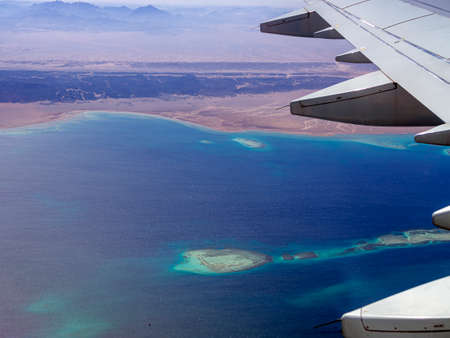 Aerial view above the clouds and sky, Inspiration concept. Travel freedom by air. Flight, view from the airplane to tropical sea with corals. Turbo-jet aircraft engine, transport 4k. Passenger airbusの写真素材