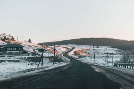 The winding road disappears behind the beautiful juniper tree in the sunny and frosty winter...