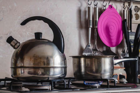 Metal Kettle and pot on a burning gas stove in kitchenの写真素材