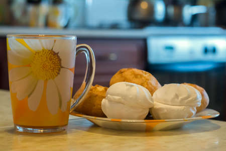 morning tea in a yellow mug with marshmallows and buns on a blurred backgroundの写真素材