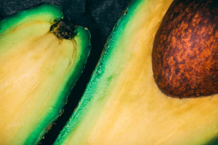 Top view close up of a half ripe avocado on smooth black surface. Clean eating and healthy diet conceptの写真素材