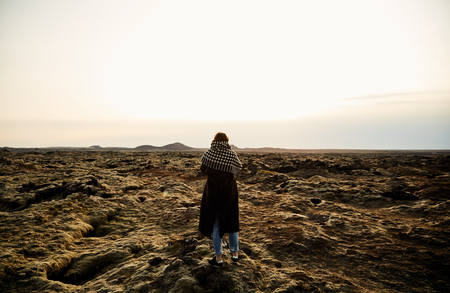 A young girl stands with her back and takes pictures of the landscape. The lava fields in Iceland....