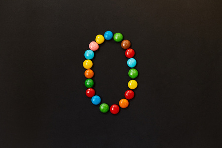 English Alphabet made of colored candies. The letter O. On a black backgroundの写真素材