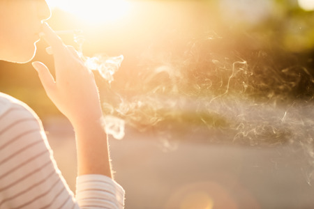 girl holding a Smoking cigarette at sunsetの写真素材