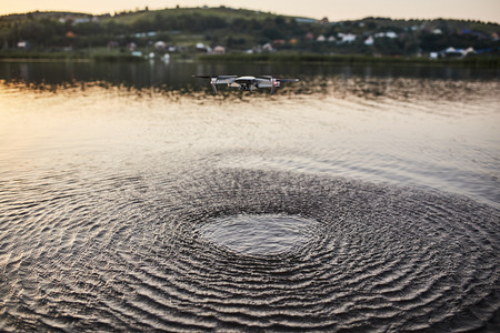 The drone hovered over the water. quadcopter. View from above on a small smart quadcopter hovering...