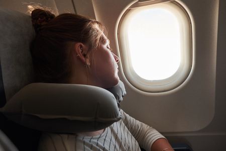 A young Girl sleeping on a plane. Passenger sleeping in an airplane on an inflatable pillow.の写真素材