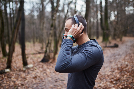 Athlete Jogging in the woods. A young man with headphones running in the woods. Autumnの写真素材