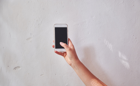 Mobile phone in female hand on the white background . Close-up.の写真素材