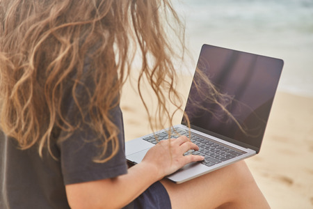 Young girl working at the computer on the beach. The freelancer working on the beach. Beach of the Indian ocean. Sri-lanka.の写真素材