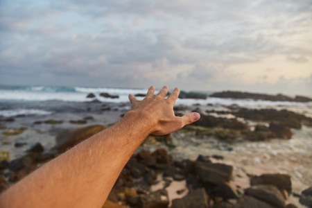 the guy reaches out to the clouds. The guy pulls his hand to the sea. Sri-lanka.の写真素材