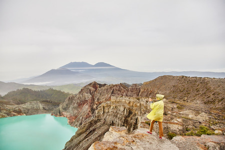 A girl on top of a volcano photographs a crater. View of the volcano.