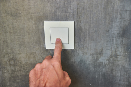 Man hand, to turn off the light, switch, front view.