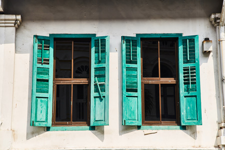 Windows with vintage shutters against a white wall.