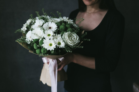A bouquet of white chrysanthemums in the hands of a woman.の写真素材