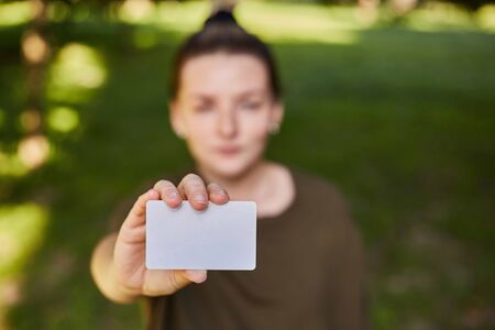 Girl holding a white credit card in her hands for shopping. Close-upの写真素材