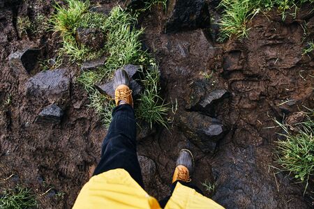 A young man stands on the stones in rubber boots. Iceland.の写真素材