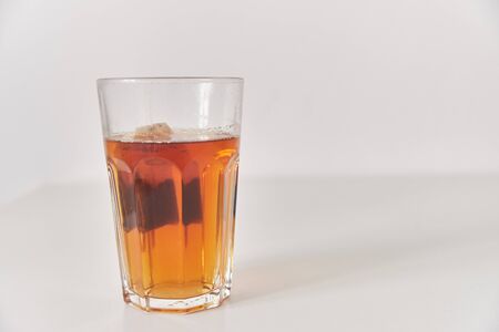 A glass of tea on the table. Close-up. Glass on a plain background.