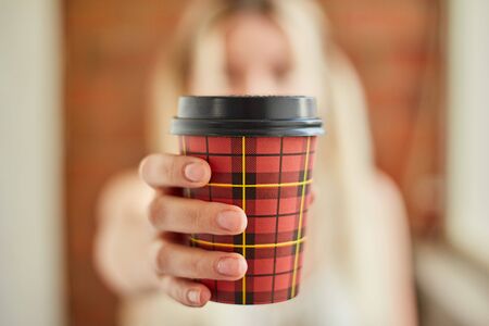 Young girl holds a glass with coffee in the foregroundの写真素材