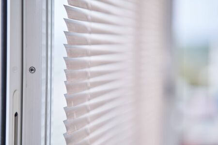 Closeup view of window with horizontal blinds. White Roller Blinds or Louver curtains at the glass windowの写真素材