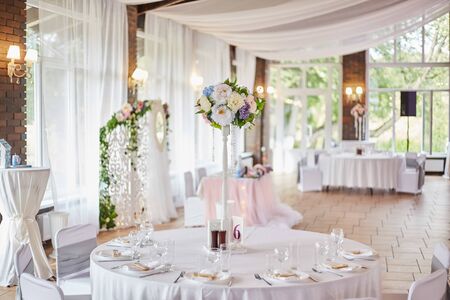 Plates with glasses on a table with a white tablecloth. Decor wedding celebration. Table settingの写真素材