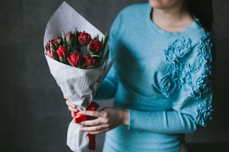 A bouquet of red flowers in the hands of a woman.の写真素材