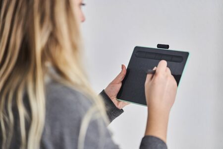 A young girl draws on a graphics tablet. Freelancer works in a cafe.の写真素材