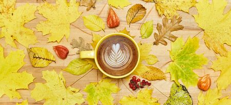 Autumn flat lay composition with dry leaves wreath frame and coffee latte cup on wooden background....