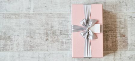 Pink gift box with a bow on a wooden background. Copy space, Banner.