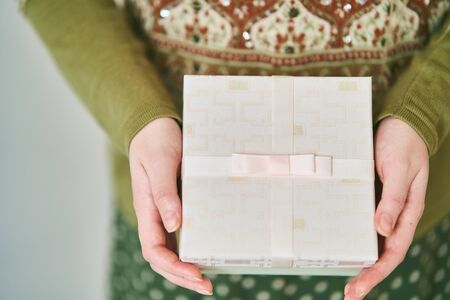 A girl holds a gift box on a white background. Close-up.
