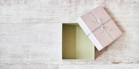 Light Pink gift box with a bow on a wooden background.