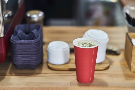 red paper cup with coffee in a coffee shop.